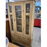 20th cent. Stripped pine display unit, two opening doors over two drawers. Approx. 67ins. x 35ins. x