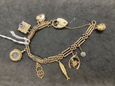 Jewellery: Yellow metal three bar gate bracelet with eight assorted charms attached having a padlock