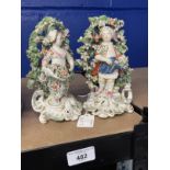 18th cent. Derby: Figures of boy and girl standing in a floral bower on raised scroll bases, a pair.