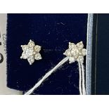 Jewellery: Diamond and white metal earrings in the form of floral clusters each set with seven