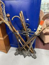 Coalbrookdale style cast iron stick stand with an assortment of wooden walking sticks, a lacrosse