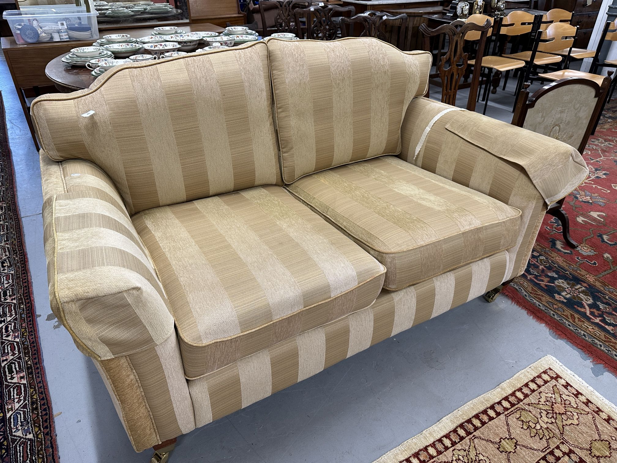 20th cent. Upholstered three-seater sofa, turned supports with cup and cover castors.