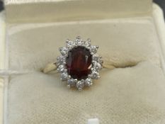 Jewellery: 9ct gold cluster set with an oval garnet surrounded by twelve white sapphires, hallmarked