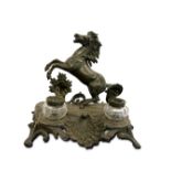 PRANCING HORSE INKWELL, EARLY 20TH CENTURY on a rounded base decorated with a plant arabesque and a