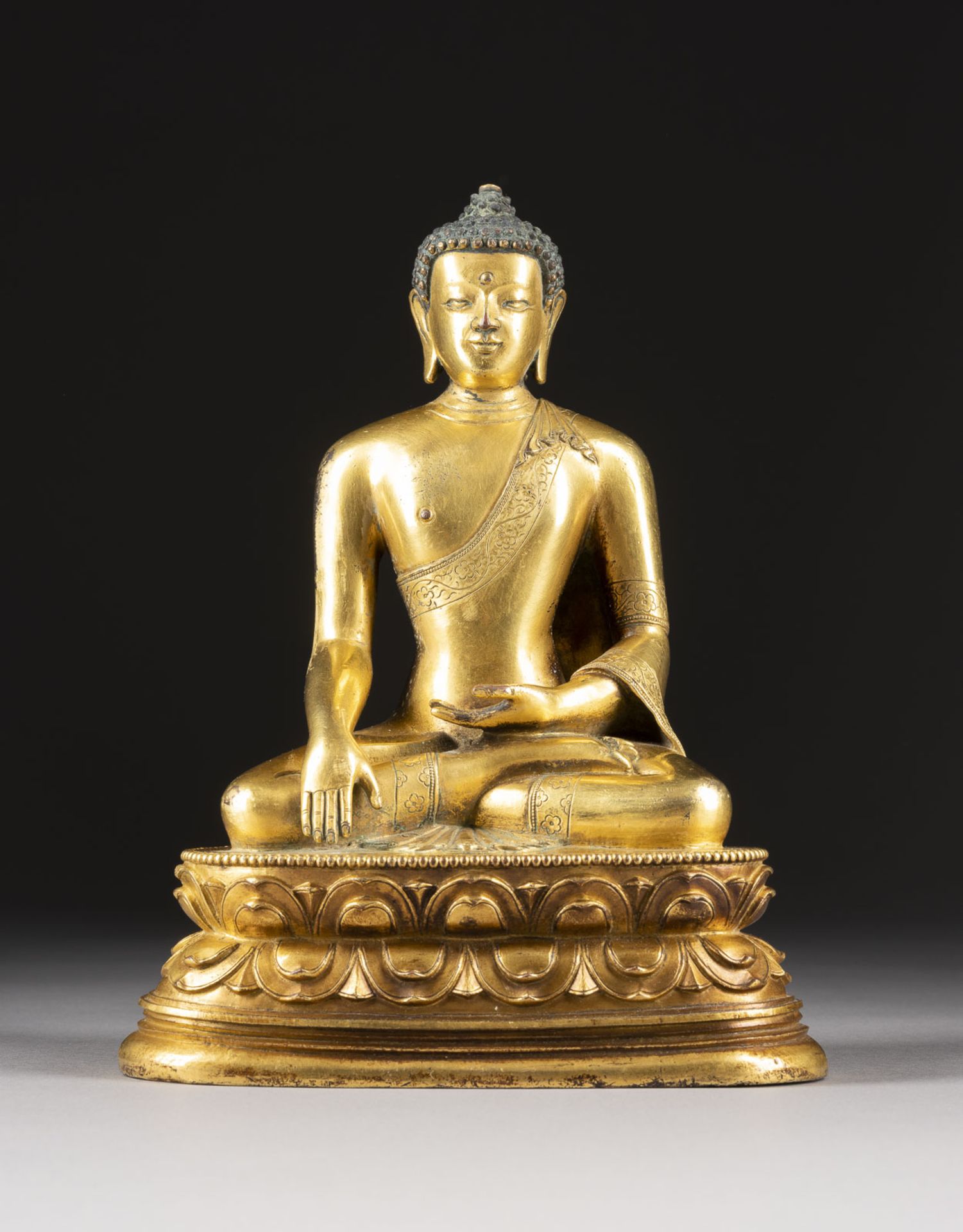 EINE VERGOLDETE SITZENDE FIGUR VON SHAKYAMUNI AUS BRONZE