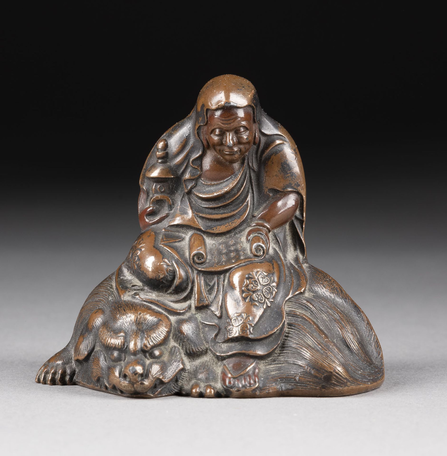 EINE FIGUR DES DARUMA AUF LÖWEN AUS BRONZE