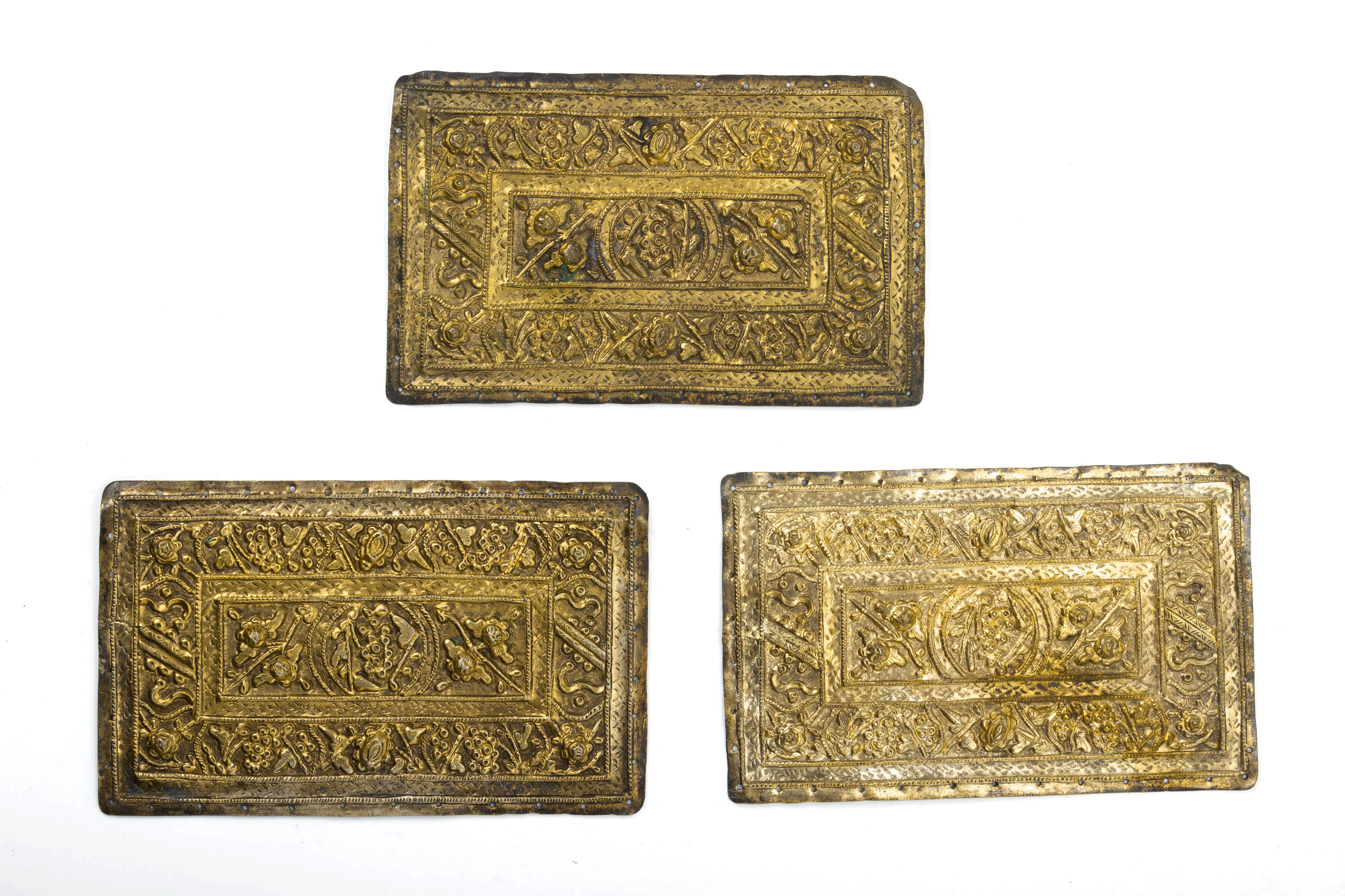 A SET OF THREE REPOUSSE SILVER GILT PILLOW ENDS