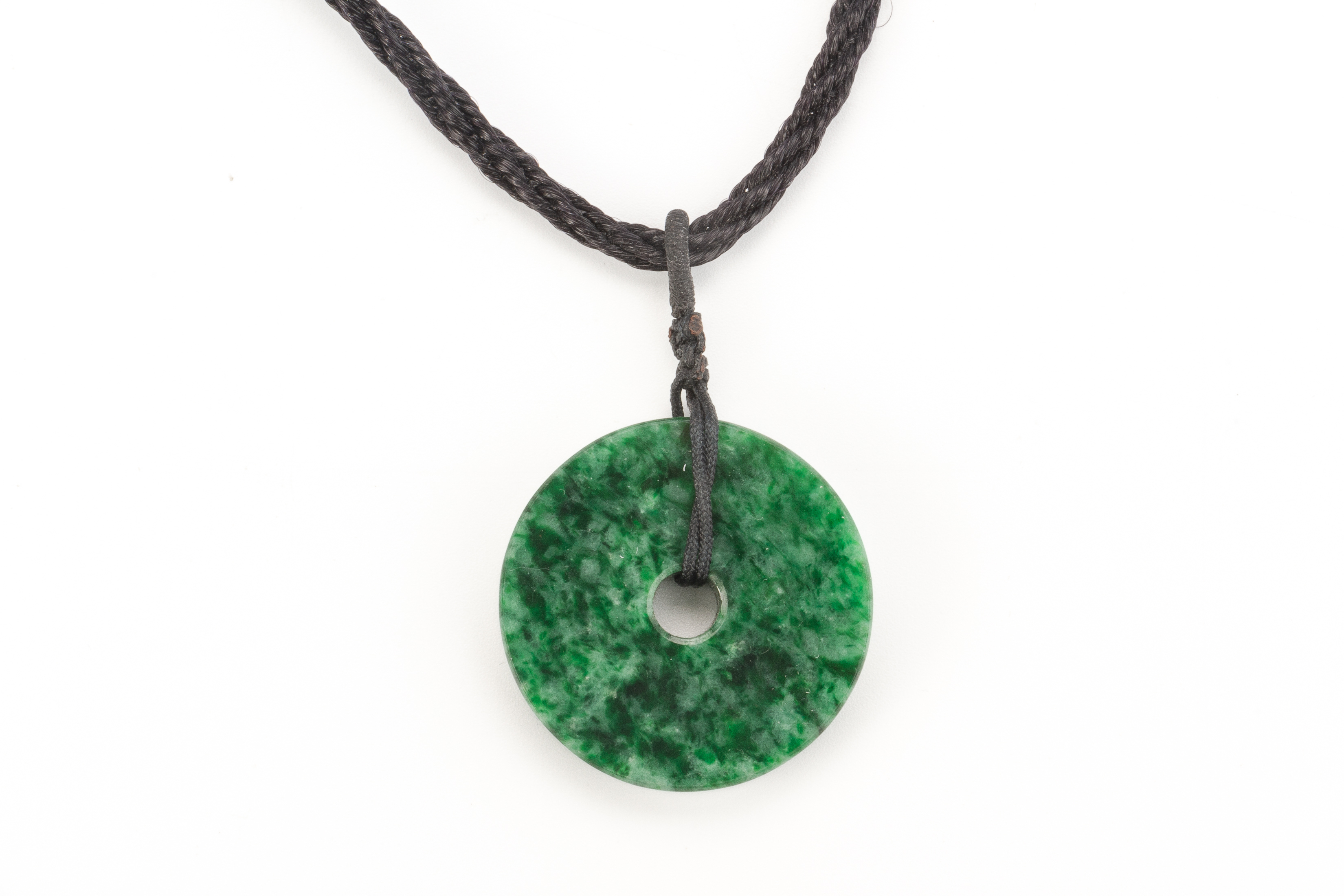 A TYPE A JADEITE DISC FORM PENDANT ON CORD