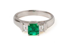 AN EMERALD AND DIAMOND THREE STONE RING