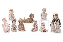 A GROUP OF NINE BISQUE PORCELAIN 'PIANO BABIES'