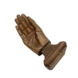 Antique prosthetic wooden hand with metal base, mounted onto a wooden plinth.