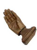Antique prosthetic wooden hand with metal base, mounted onto a wooden plinth.