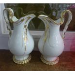 A pair of large porcelain jugs with gilded decoration, under glaze cracks to one, 25cm