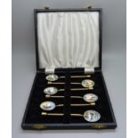 A cased set of six gilt metal spoons, each bowl enamelled with bird detail