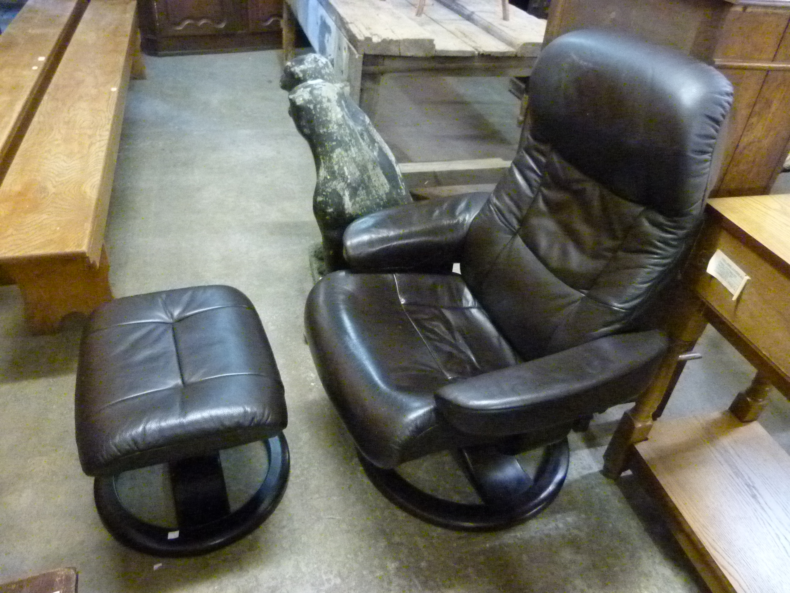 A black leather revolving lounge chair and stool