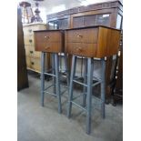 A pair of afromosia two drawer chests on metal stands