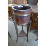 An early 20th Century oak and brass bound barrel shaped jardiniere on stand