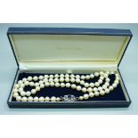 A long string of large cultured pearls on a silver and paste clasp, approximately 82cm long,