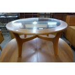 A circular teak and glass topped coffee table