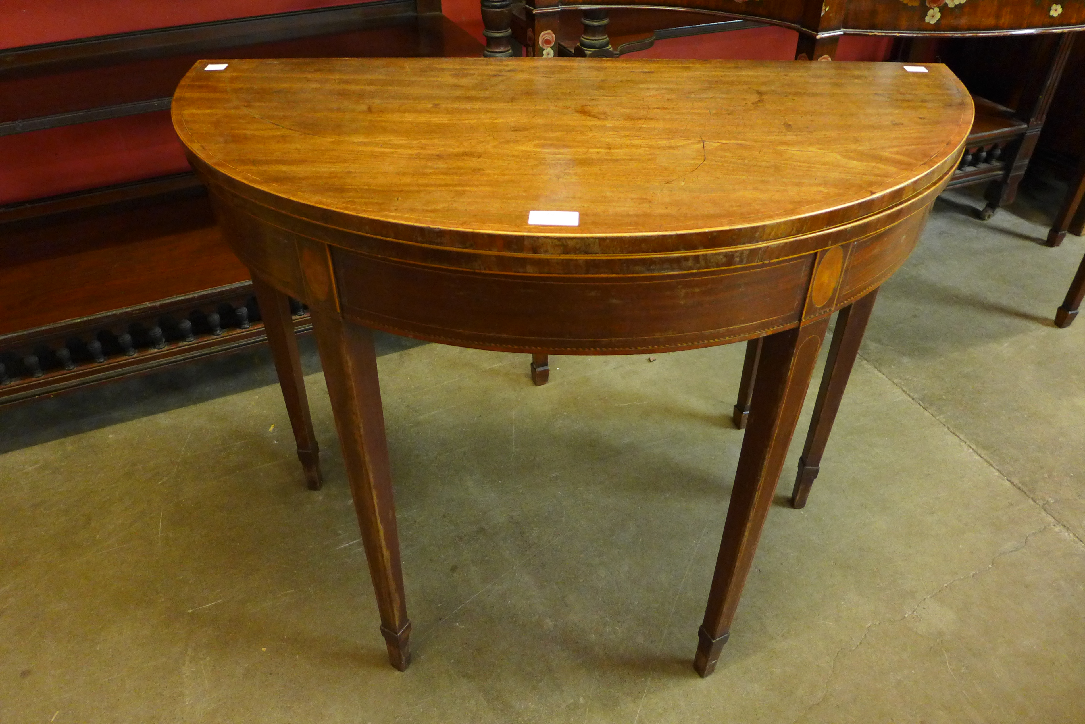 A George III inlaid mahogany demi-lune fold over tea table