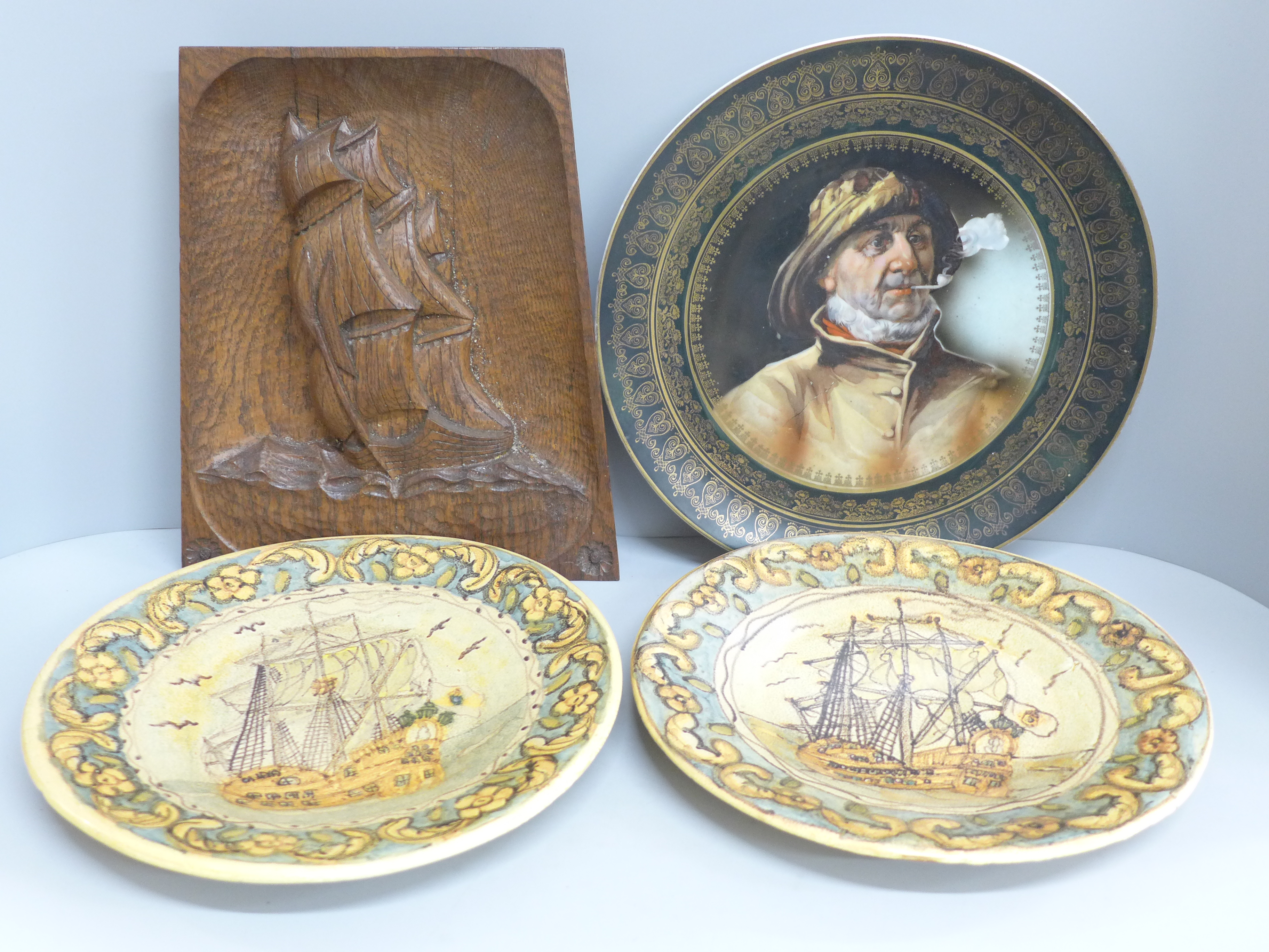 An Arts and Crafts style carved wooden plaque, two Portuguese plates and a charger with portrait