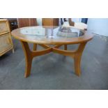 A circular teak and glass topped coffee table