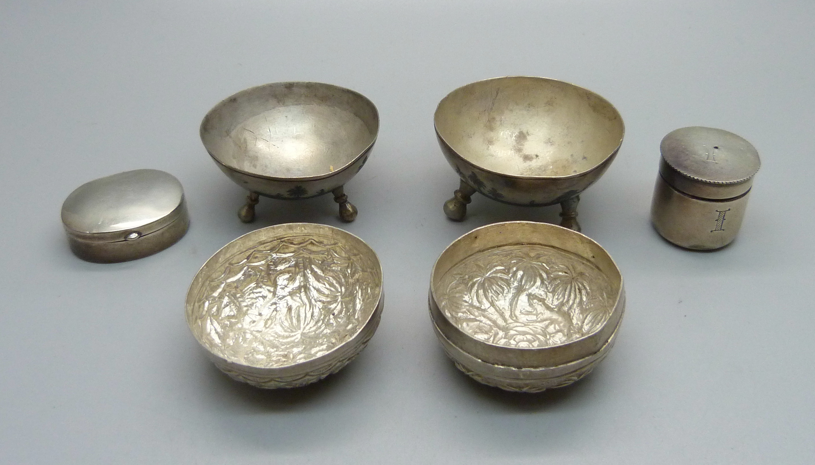 Two silver boxes, one with screw top, two white metal salts with Nile scene decoration and a white