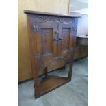 A small carved oak corner cabinet