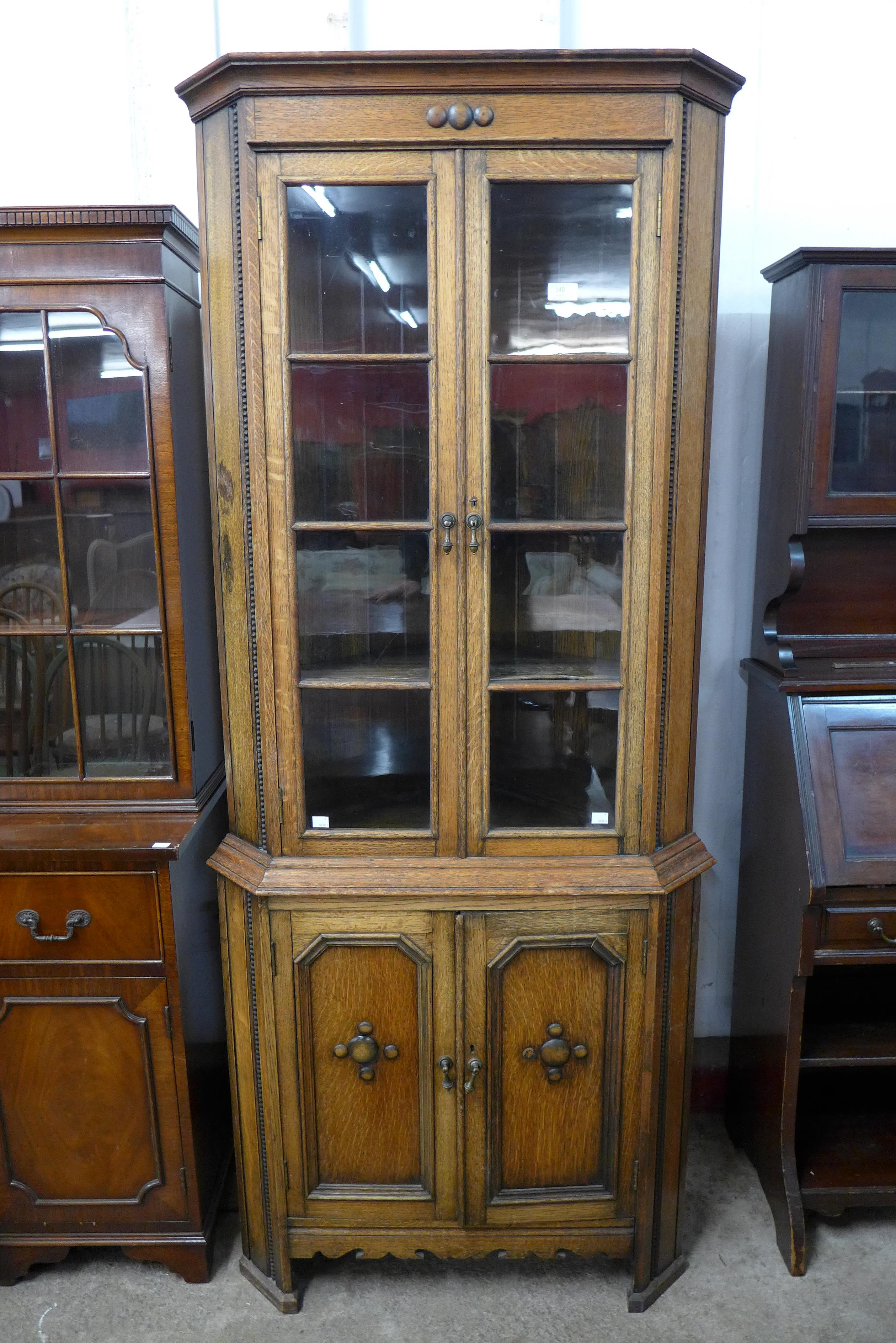 An early 20th Century oak freestanding splay front corner cabinet