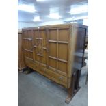 An Art Deco carved oak three door nursery cupboard