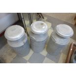 Three aluminium milk churns and covers