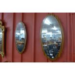 A pair of oval teak framed mirrors