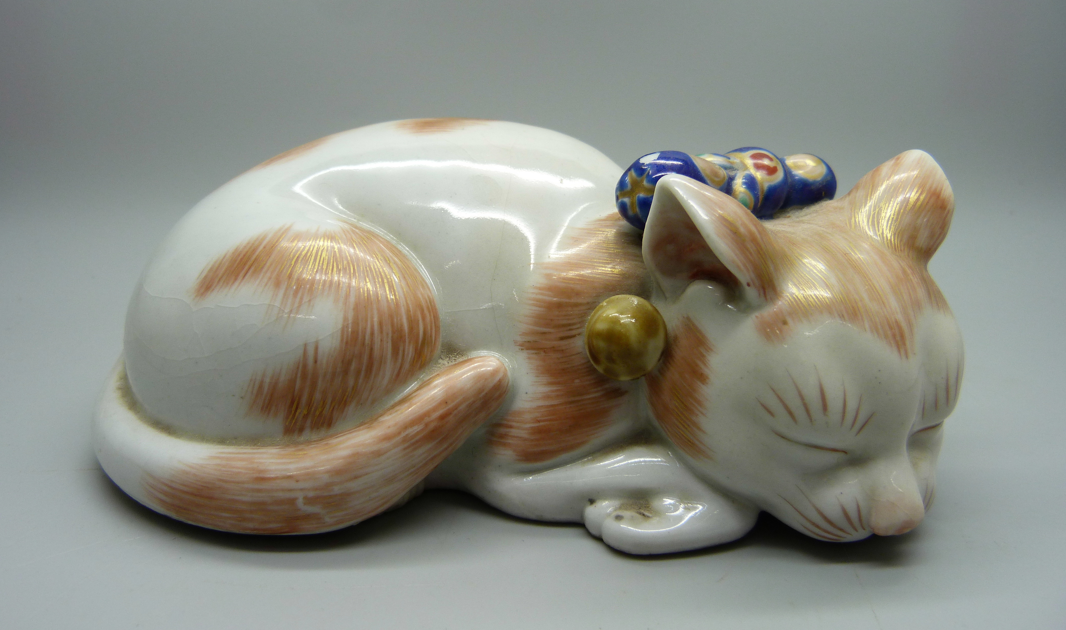 A Japanese Taisho period Kutani porcelain model of a sleeping cat, 15.5cm