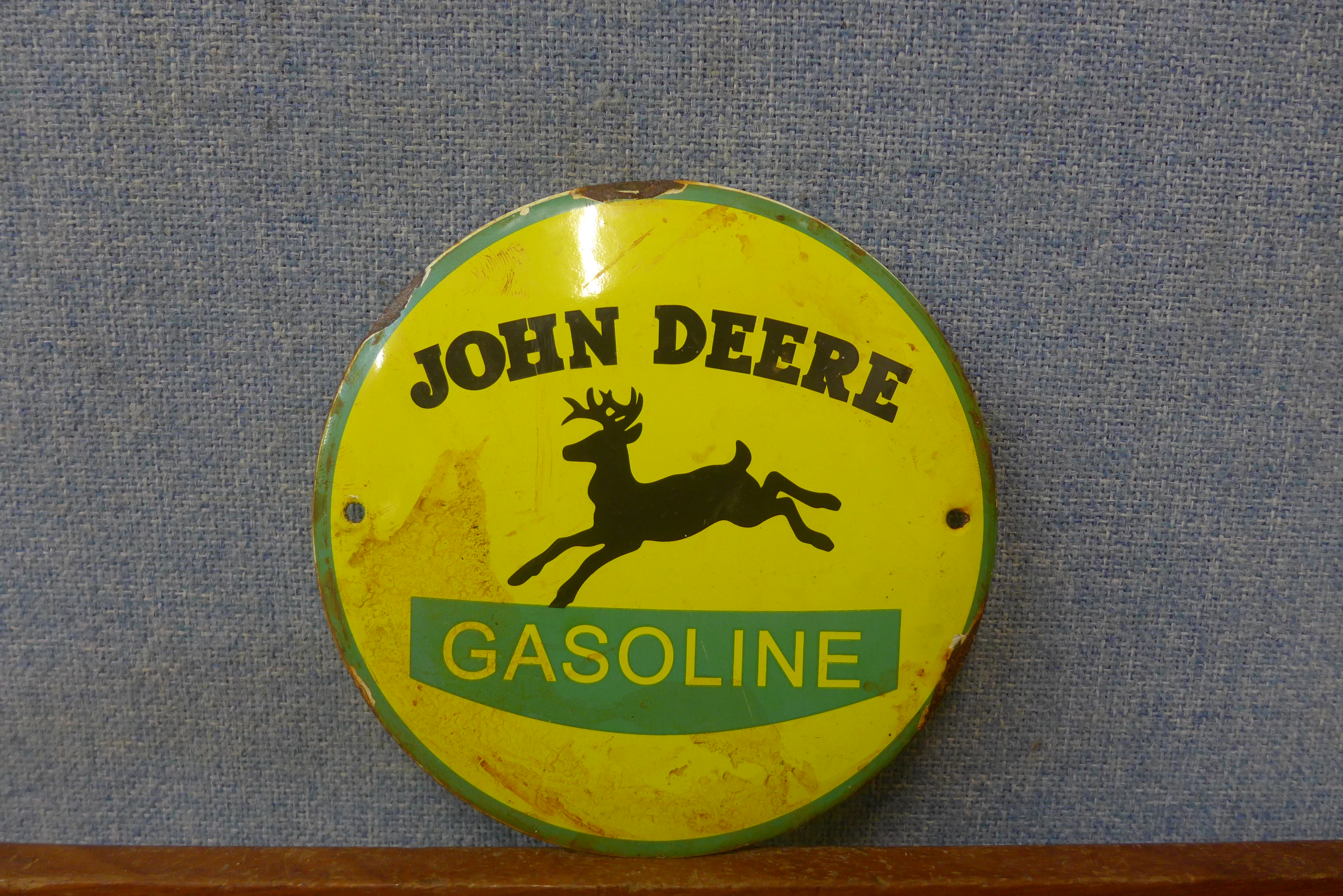 A John Deere enamelled signa and a tractor steering wheel