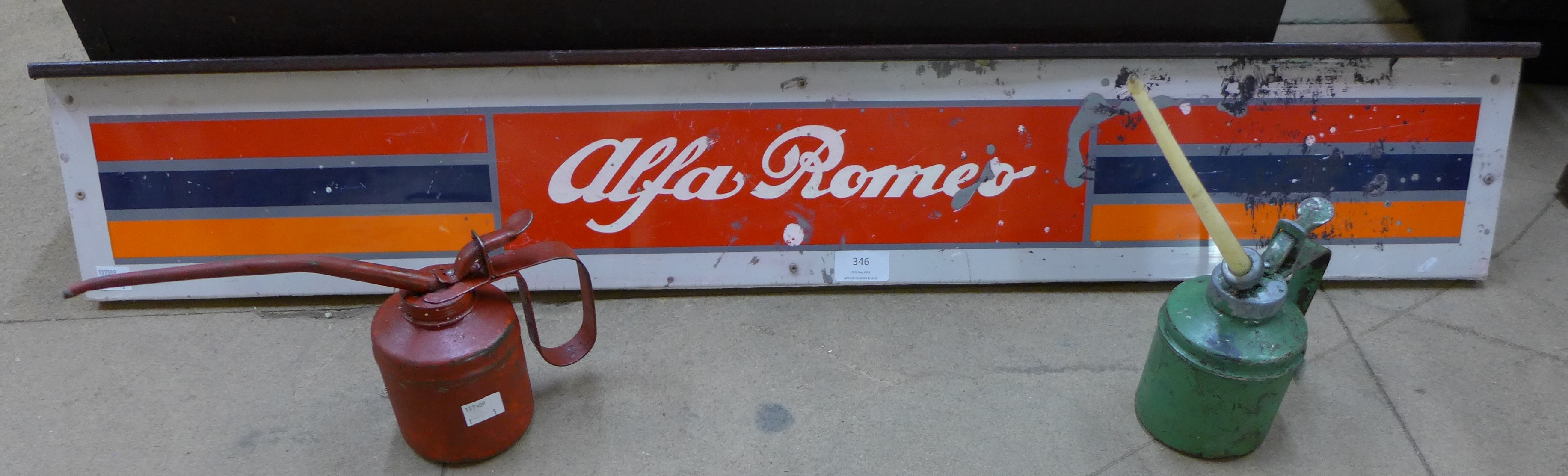 A metal Alfa Romeo sign and two oil cans