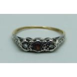 An 18ct gold and three stone garnet and diamond ring, 1.7g, L, shank worn