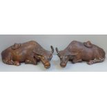 A pair of Chinese carved wooden models of water buffalo, both with damaged horns and splits to body,