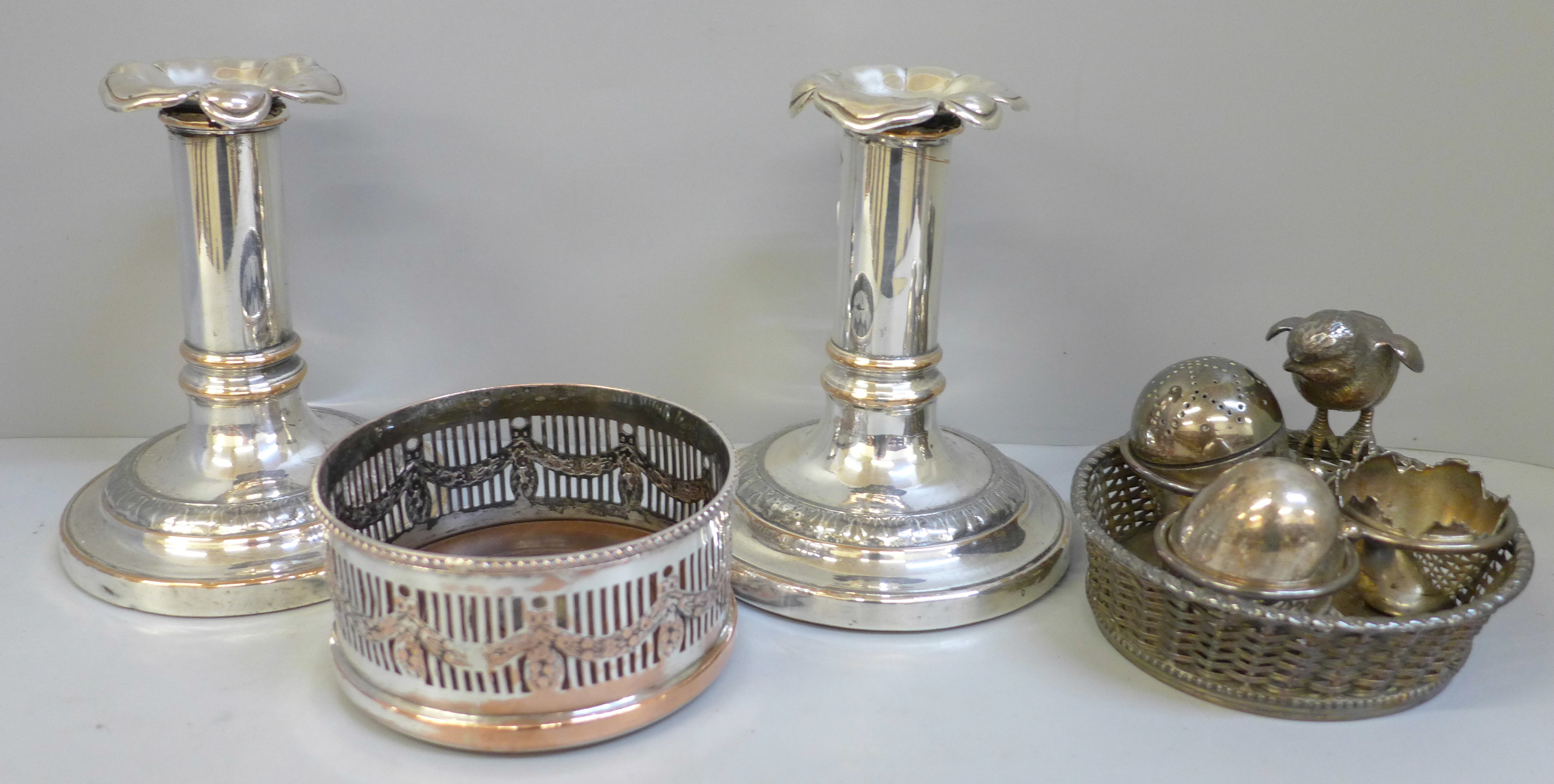 A pair of silver plated candlesticks, a Mappin & Webb egg cruet and wine coaster