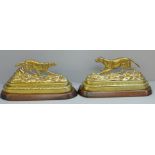 A pair of Victorian brass gun dogs on mahogany bases with traces of original gilding, 21cm