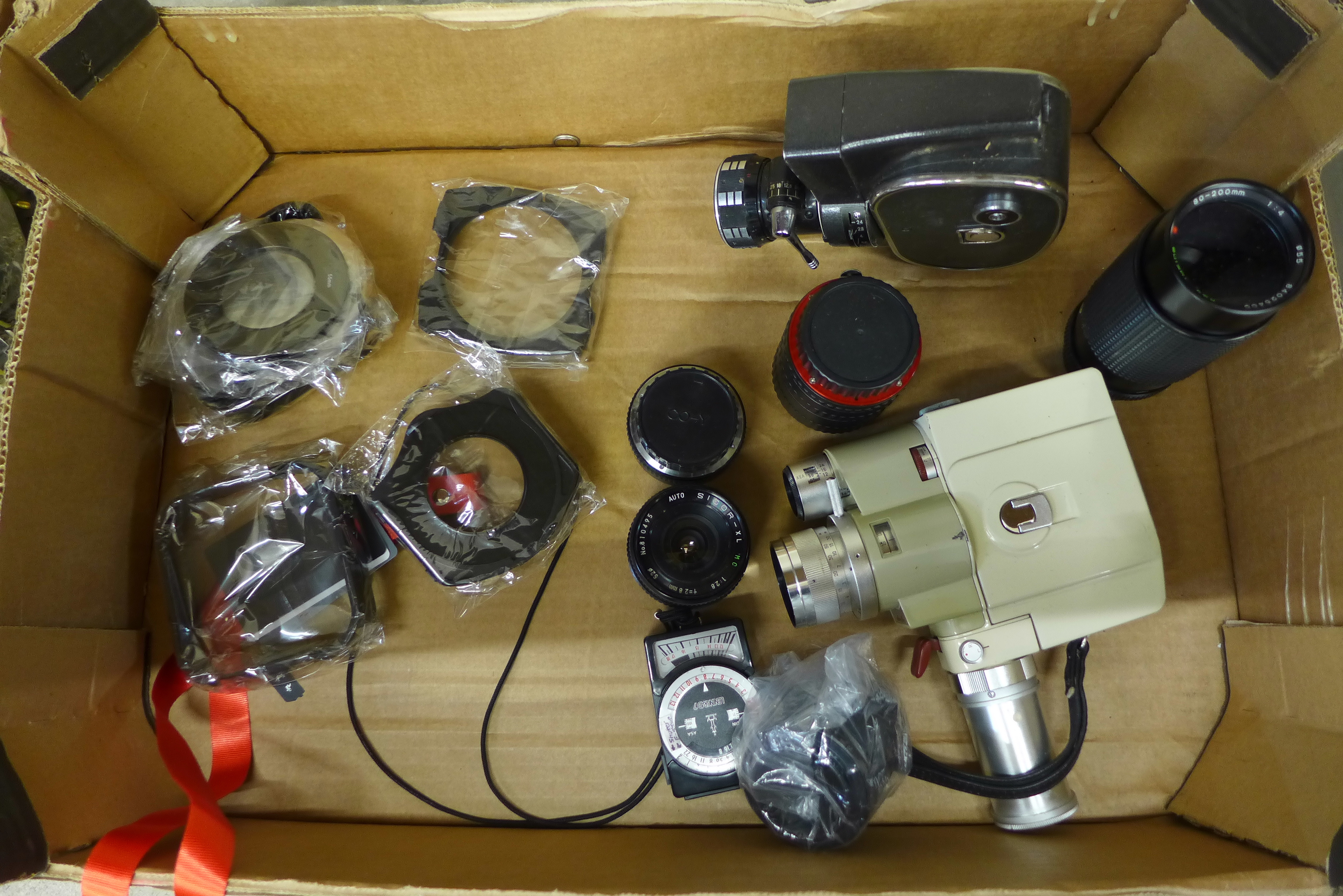 A bag of mixed camera lenses and accessories and two cine cameras