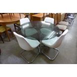 A chrome and smoked glass topped circular dining table and four white vinyl chairs