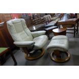 A Norweigan Ekornes Stressless beech and cream leather revolving lounge chair and stool