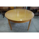 A circular teak extending dining table