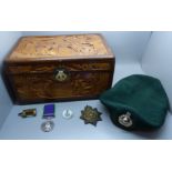 A carved wooden box, a military beret with cap badge, other badges and a For Campaign Service