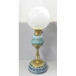 A brass oil lamp with blue glass reservoir and pottery base, replacement shade