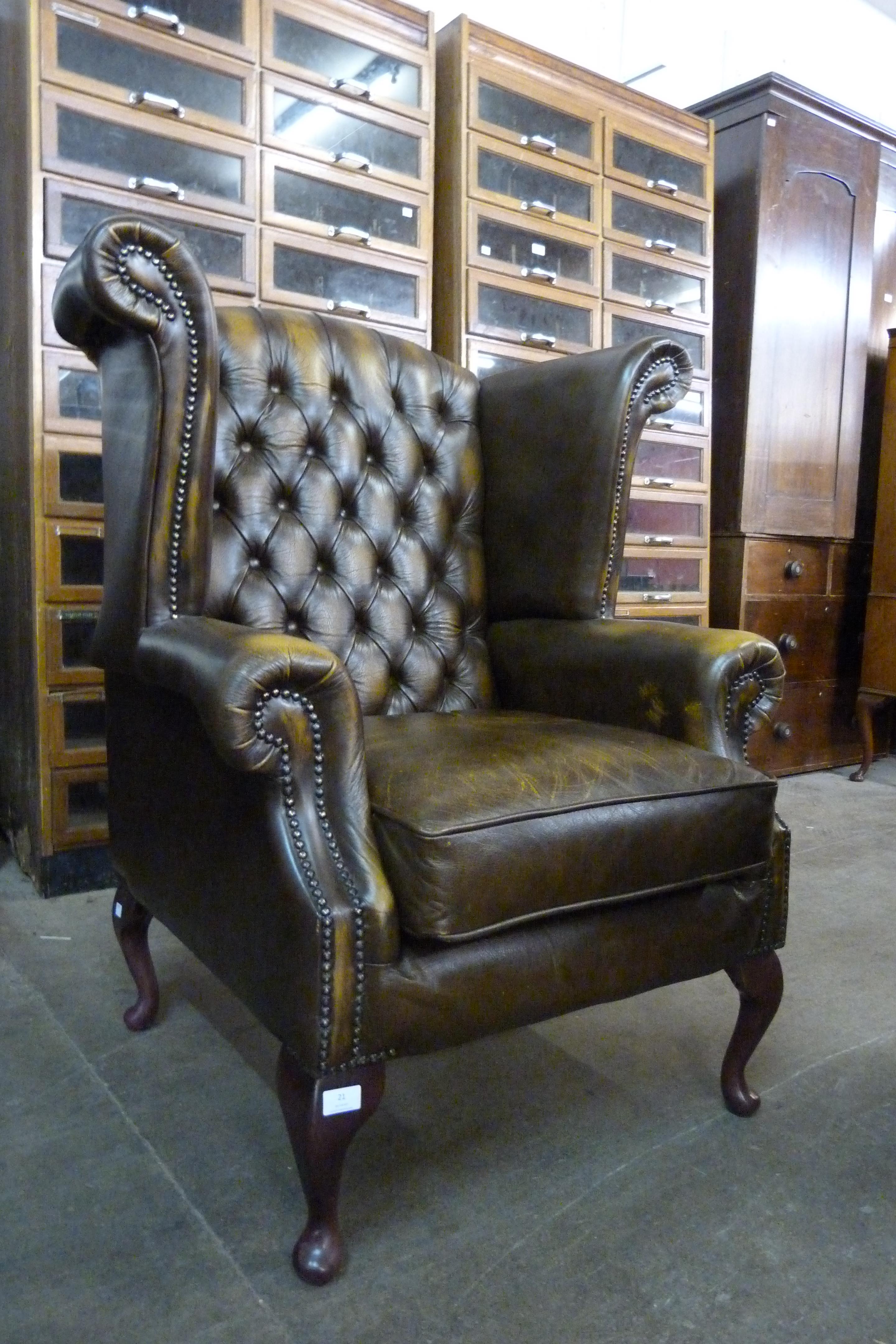 An olive green Chesterfield wingback armchair