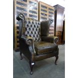 An olive green Chesterfield wingback armchair