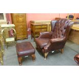 An oxblood red leather wingback armchair and matching footstool