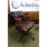 A mahogany and oxblood red leather revolving Captain's desk chair