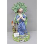 A lead-glazed Staffordshire pearlware figure, titled St. Peter, with bocage, Peter kneels with hands
